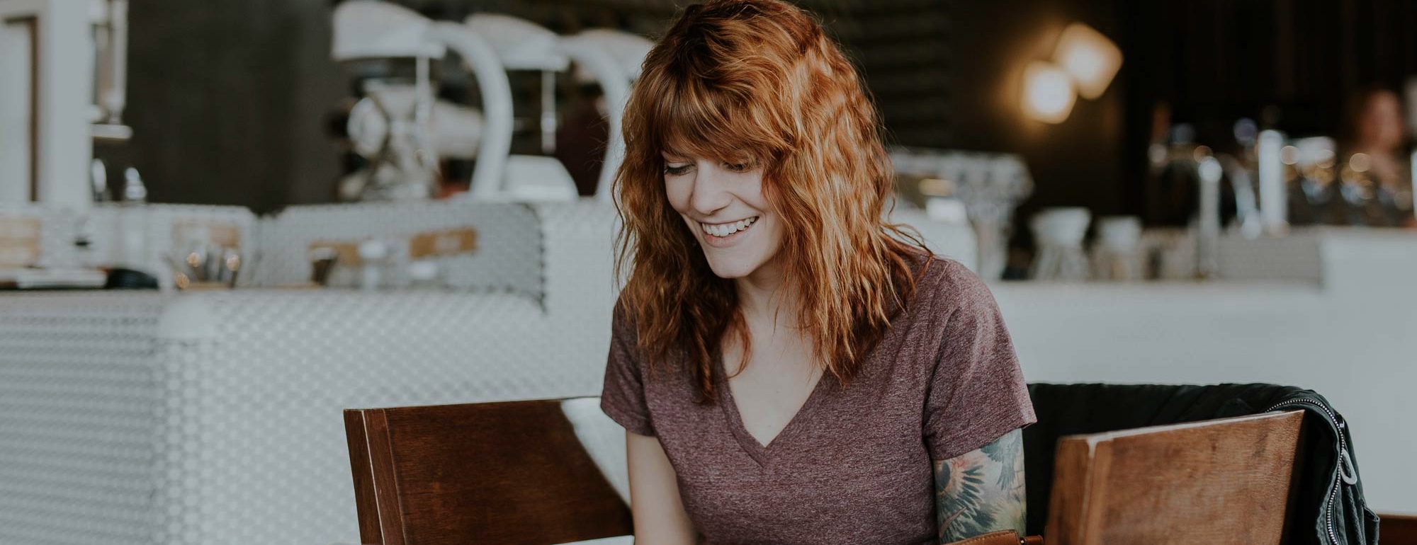 En rödhårig kvinna i t-shirt sitter på en restaurang