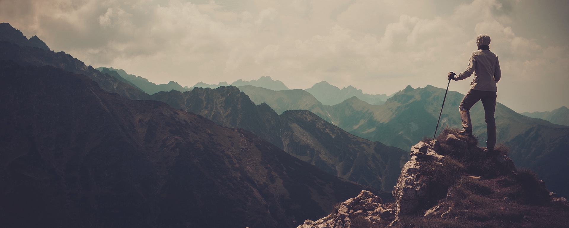 Man på en bergstopp som blickar över en bergskedja